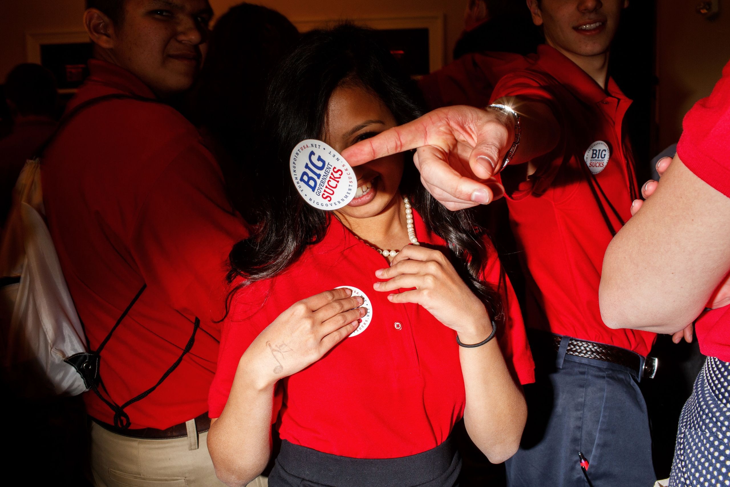 Turning Point USA Youth Activists at Work – Tumisang Bogwasi Young people in red shirts at a Turning Point USA event, with one person holding a "Big Government Sucks" sticker in front of the camera.
