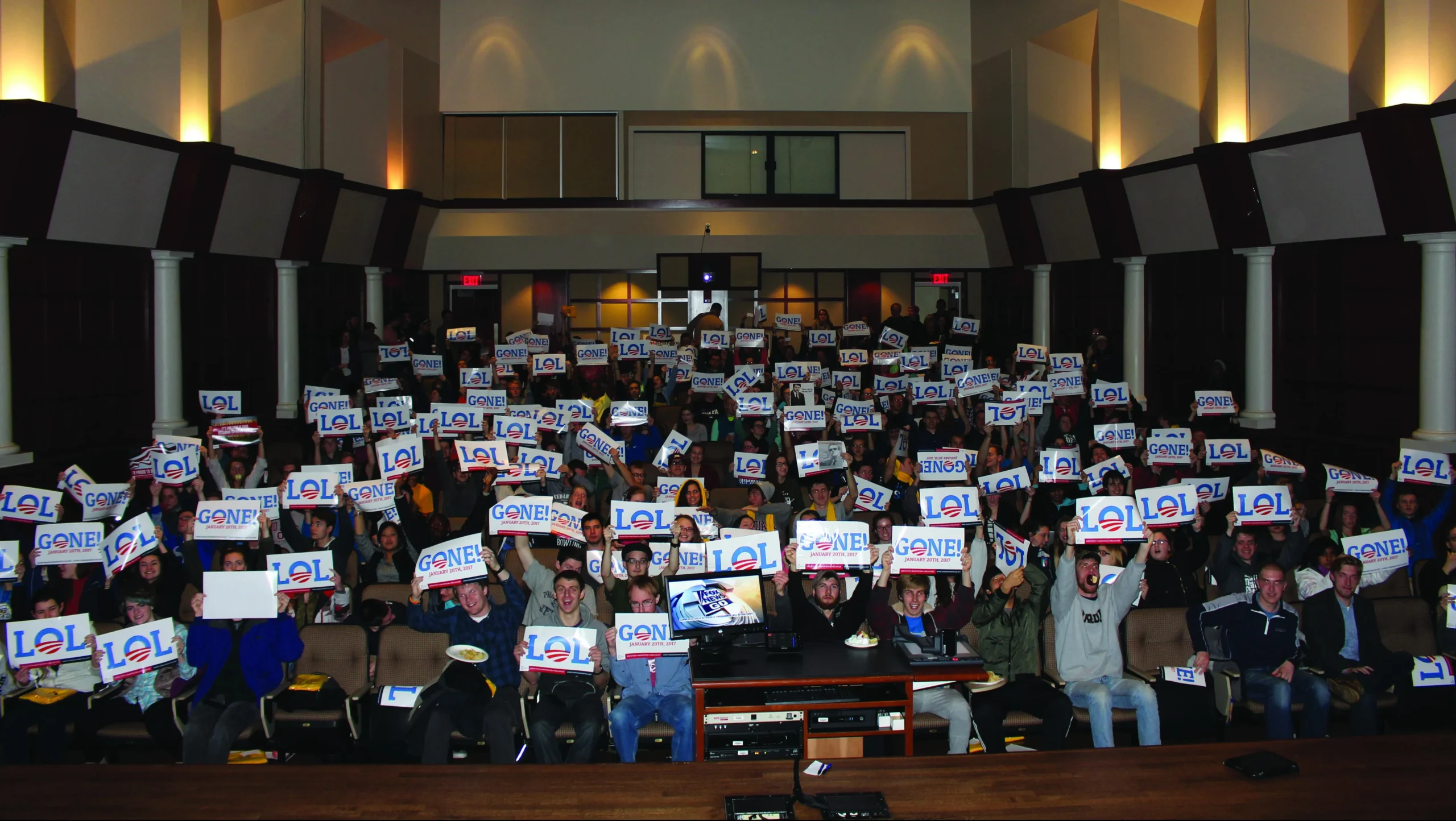 Turning Point USA Crowd Mocks Obama’s Exit with “LOL” and “GONE!” Signs – Tumisang Bogwasi Large group of people seated in an auditorium holding up signs that say “LOL” and “GONE!” with parodied Obama logos.