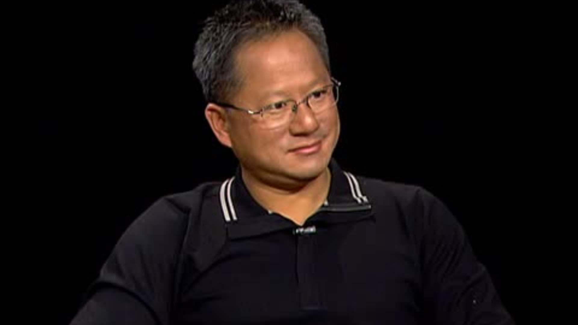 Jensen Huang 2006 – Tumisang Bogwasi Jensen Huang in a 2006 interview setting, wearing glasses and a dark shirt, speaking calmly against a dark background.