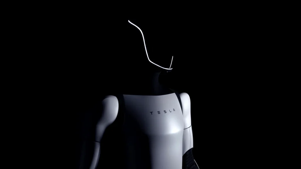 Tesla Optimus Gen 2 – Tumisang Bogwasi Tesla Optimus Gen 2 humanoid robot in a dark setting, showcasing its sleek silver body and illuminated facial outline.