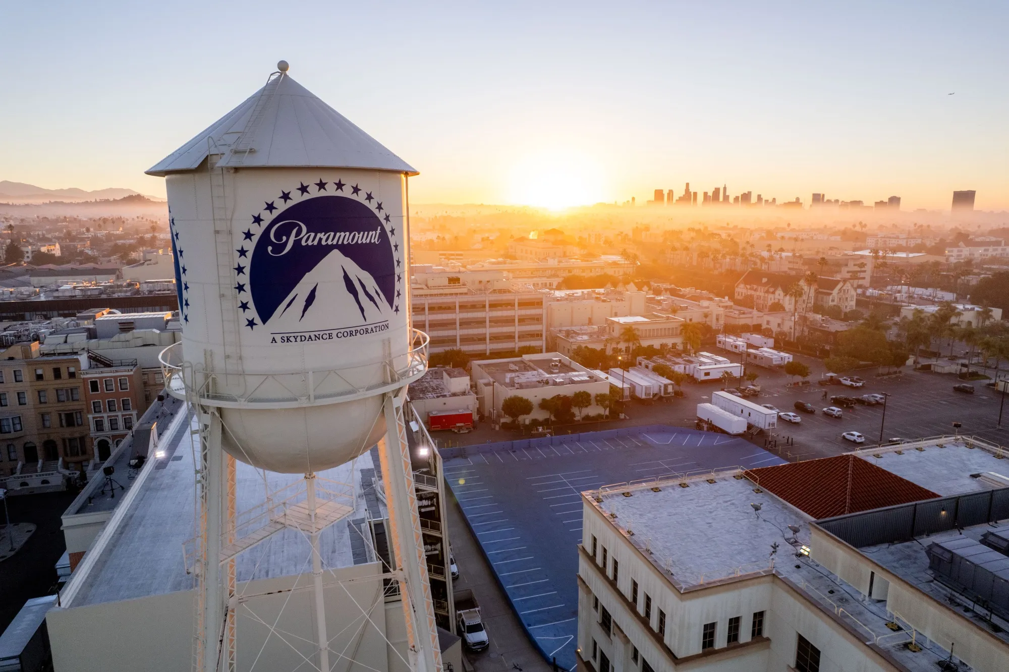 Paramount Studios Water Tower at Sunrise Over Hollywood – Tumisang Bogwasi Aerial view of the Paramount Studios water tower at sunrise, overlooking Los Angeles and the Hollywood skyline.