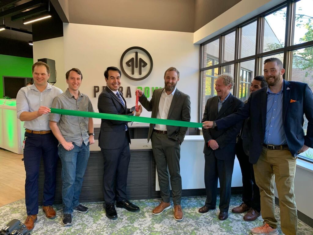 Petra Power co-founders, Partners, and Local Leaders cutting a green ribbon at their new headquarters, joined by local leaders and partners.