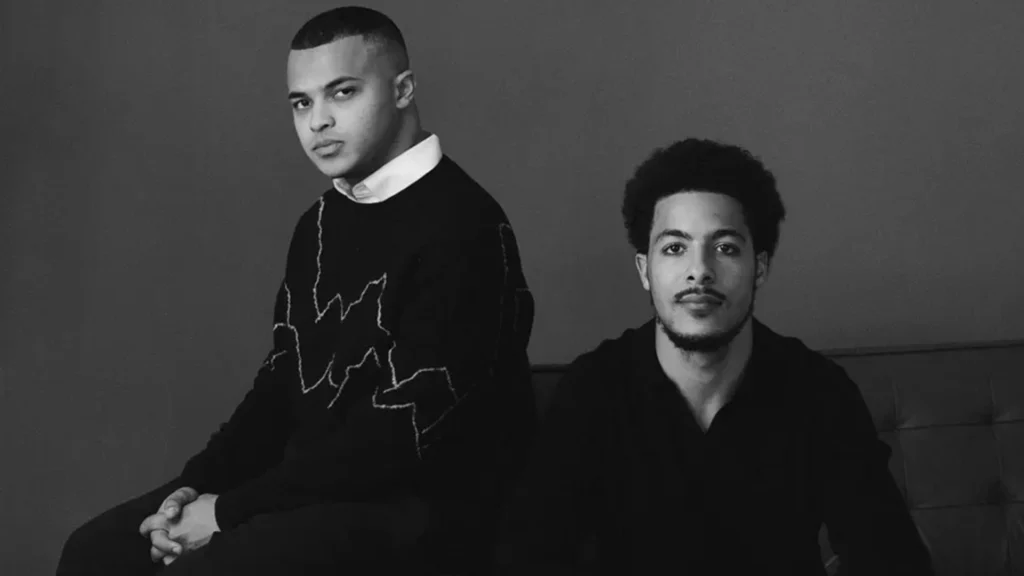 Black-and-white portrait of POSH founders Avante Price and Eli Taylor-Lemire seated together in a studio setting.