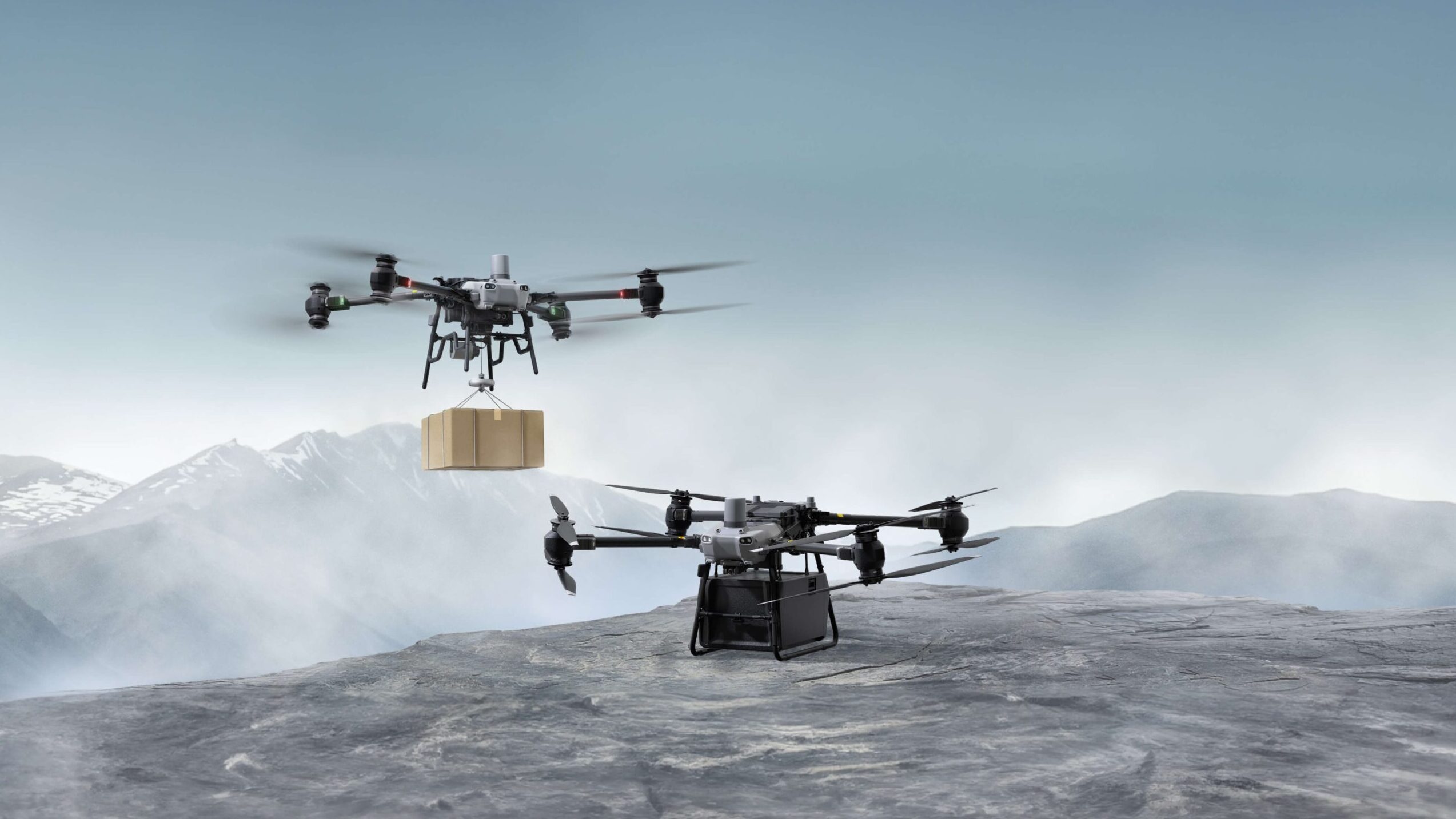 Autonomous Aerial Logistics in Complex Terrain – Tumisang Bogwasi Two autonomous multirotor drones operate in a mountainous landscape, with one drone carrying a suspended cargo package and another positioned on rocky ground, demonstrating autonomous aerial logistics.