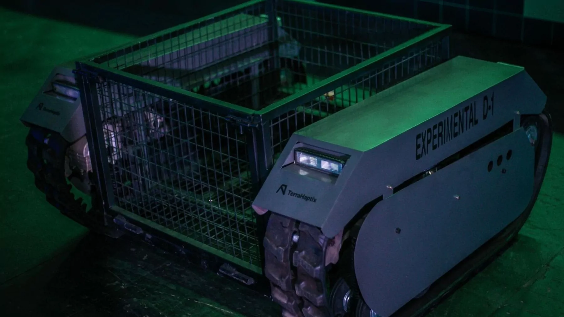 DUMA Autonomous Ground Mobility in Low-Light Operations – Tumisang Bogwasi Terra Industries DUMA autonomous ground vehicle with tracked wheels and a modular cargo cage operating at night under green-tinted lighting during testing.