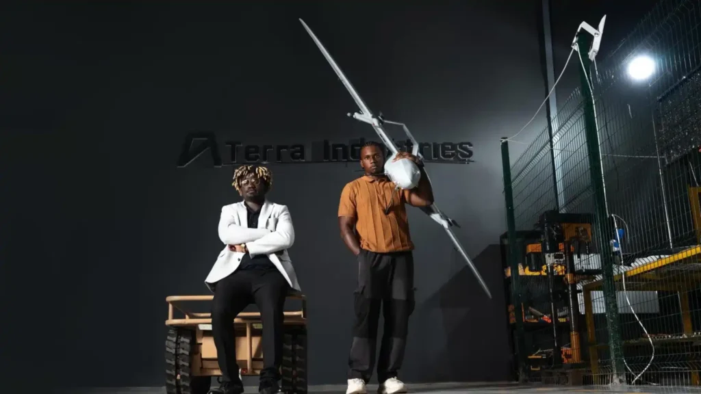 Terra Industries - Founders Nathan Nwachukwu and Maxwell Maduka – Tumisang Bogwasi Nathan Nwachukwu and Maxwell Maduka, founders of Terra Industries, stand in a robotics facility with a fixed-wing drone, highlighting their work in autonomous aerial systems.