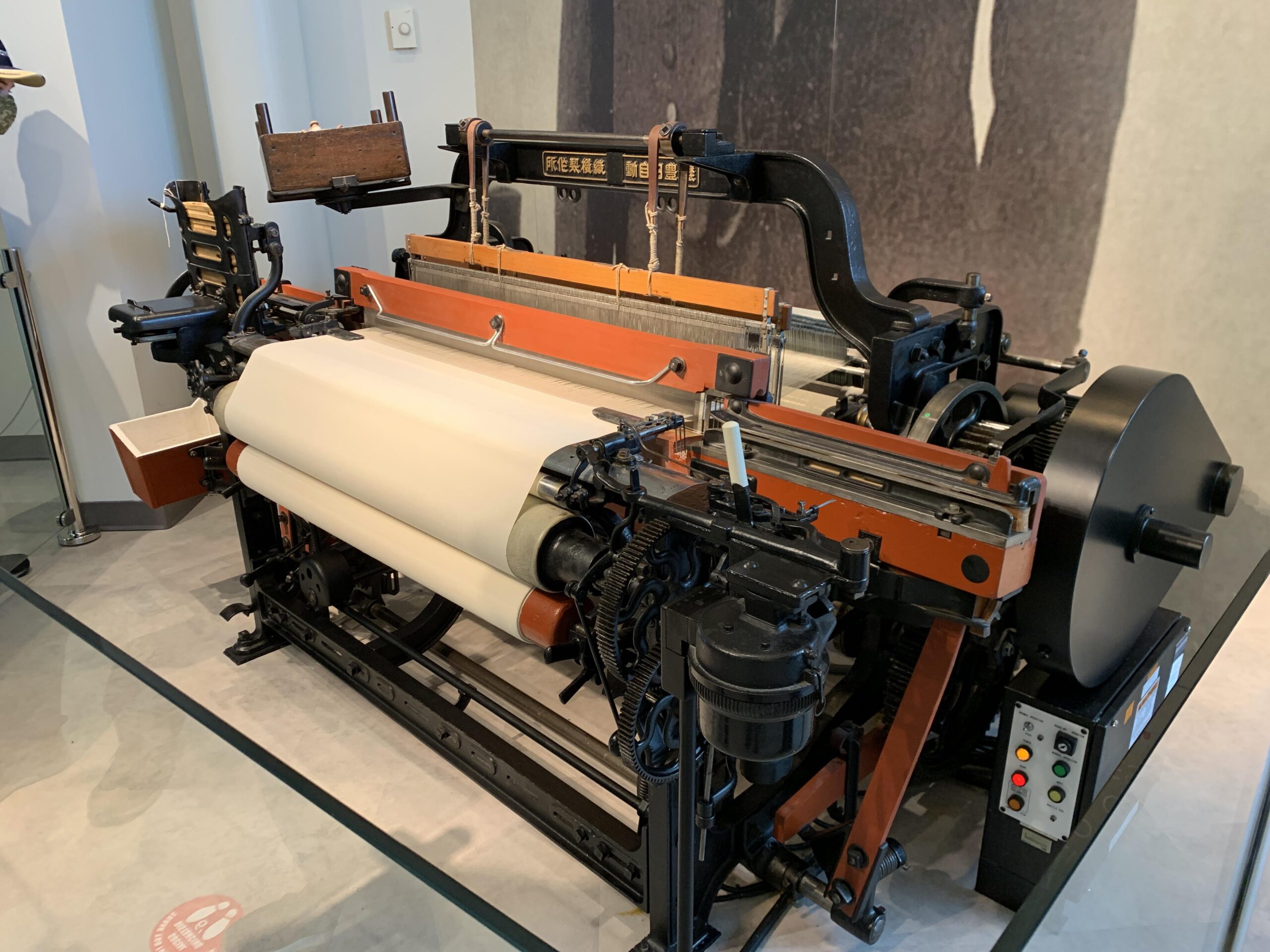 Toyoda Type G Automatic Loom on display with threads and cloth roll in a museum exhibit
