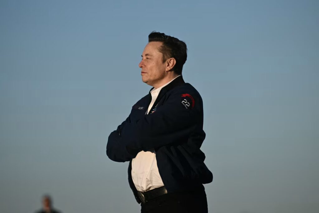Elon Musk Portrait in Dusk Setting – Tumisang Bogwasi Elon Musk wearing a black hoodie looking upward with a thoughtful expression in a dark background.