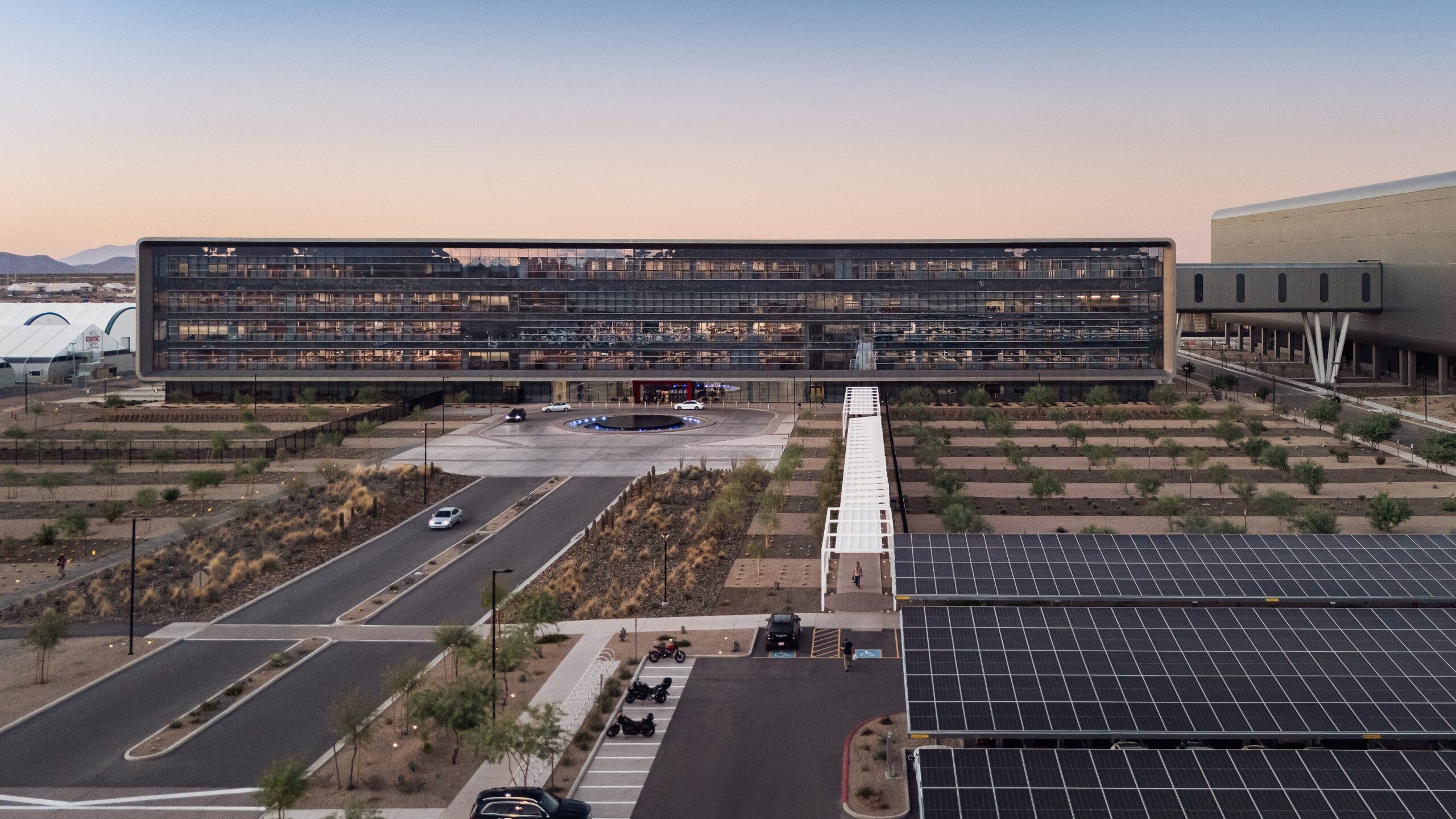 TSMC Phoenix Campus and Semiconductor Facility – Tumisang Bogwasi TSMC semiconductor facility in Phoenix Arizona with modern building and solar panels in the foreground.