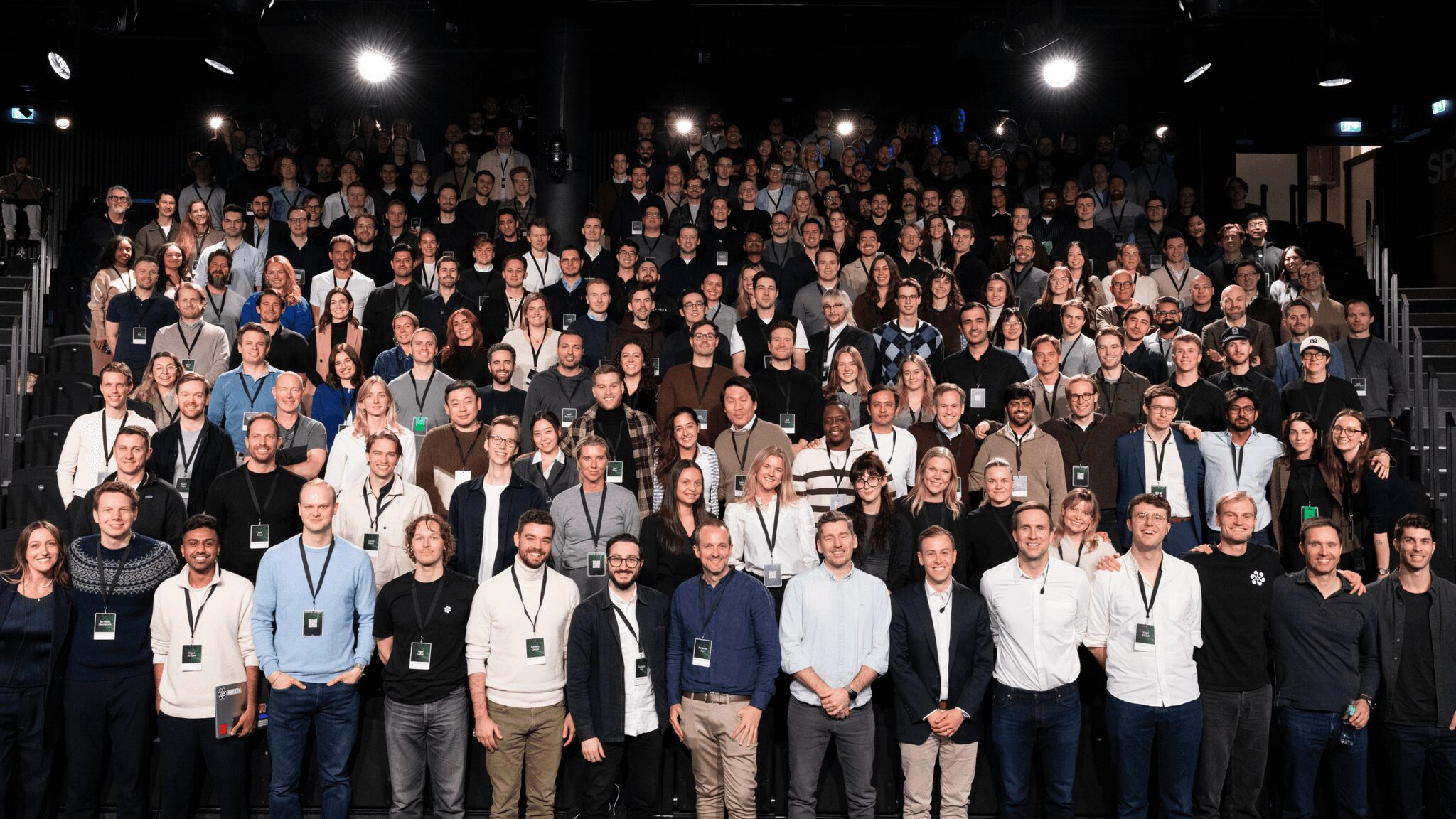 The Legora Team Driving Legal AI Innovation – Tumisang Bogwasi Large group photo of Legora employees gathered at a company event, posing together in a modern auditorium setting.