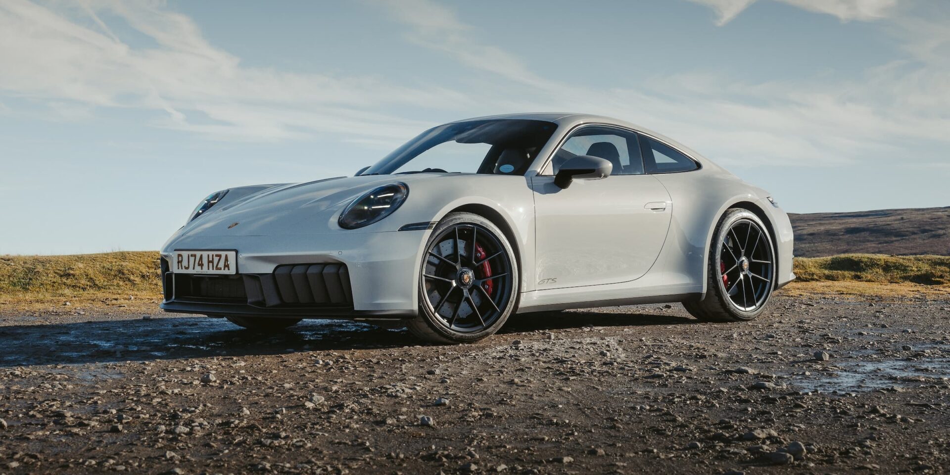Porsche 911 Carrera GTS on an Open Road – Tumisang Bogwasi Silver Porsche 911 Carrera GTS parked on a gravel road in an open countryside setting.