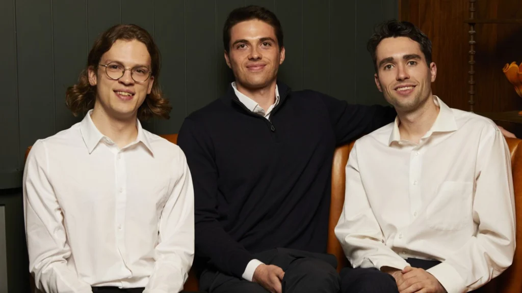Rogo AI Founders Gabriel Stengel John Willett and Tumas Rackaitis – Tumisang Bogwasi Portrait of Rogo AI founders Gabriel Stengel, John Willett, and Tumas Rackaitis seated together in business attire against a dark interior background.