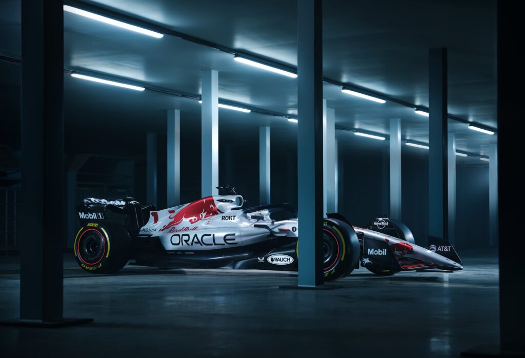 oracle-red-bull-racing-japan-2025-livery – Tumisang Bogwasi Oracle Red Bull Racing Formula One car with a white, red, and black special livery parked inside a modern industrial building under fluorescent lighting.