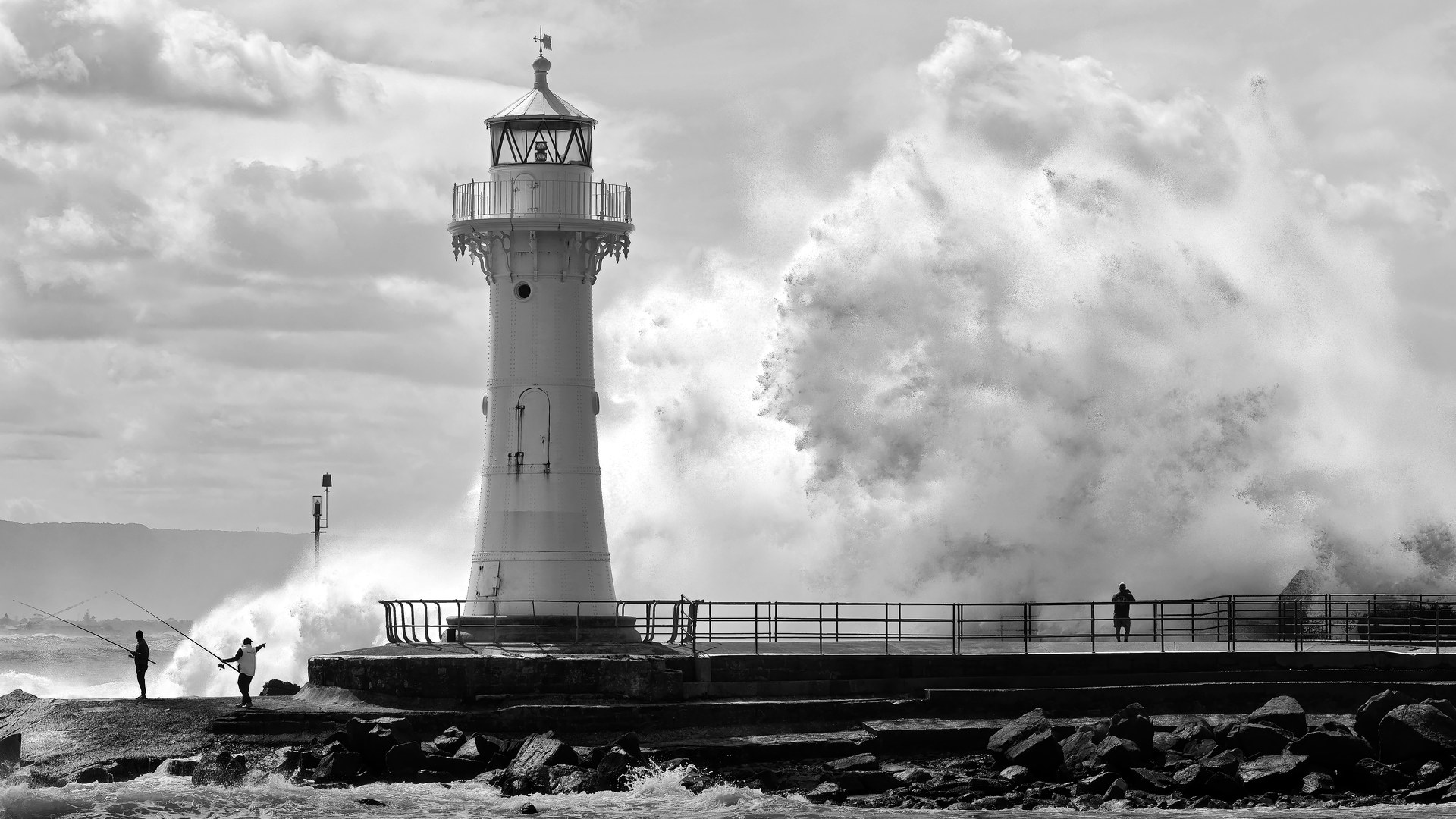 Storm waves explode over the breakwater beside the Wollongong lighthouse, in black and white